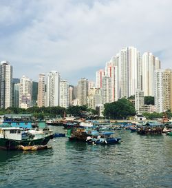 Boats moored in river against buildings and sky in city