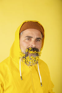 Handsome man with flower beard on yellow background person