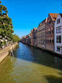 Canal amidst buildings against clear blue sky