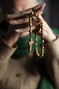 Close-up of woman holding rosary with hands clasped