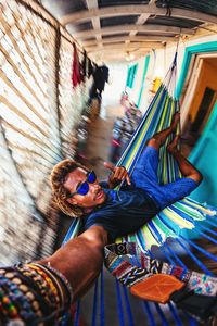 High angle portrait of young man resting on hammock at home