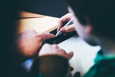 Cropped image of teacher teaching student at table