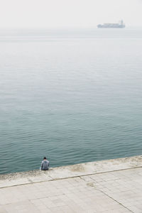 High angle view of man sitting by sea