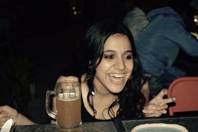 Cheerful woman looking away by beer glass on table