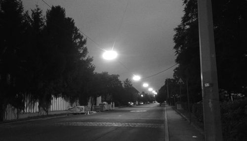 Empty road along trees at night