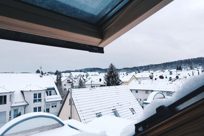 Tilt image of townscape by snow covered mountain against sky