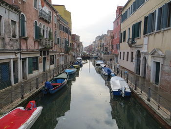 Boats moored on canal amidst buildings in city