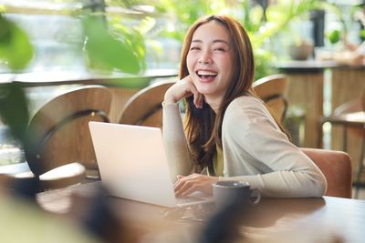 Young woman using laptop while sitting on table