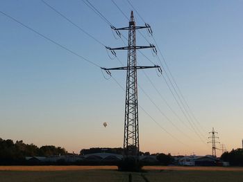 Electricity pylon against clear sky at sunset