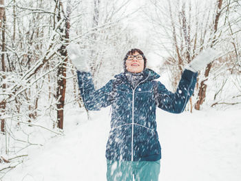 Smiling woman is playing with snow. fun in snowy winter forest. woman laughs. sincere emotions.