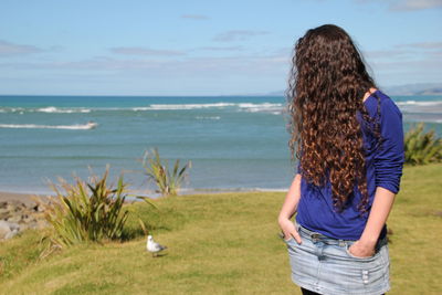 Rear view of woman looking at sea shore against sky