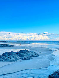 Scenic view of snow covered landscape against blue sky