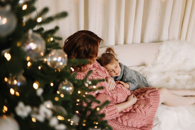 Pregnant mom and daughter child celebrate the christmas holiday in the decorated room of the house