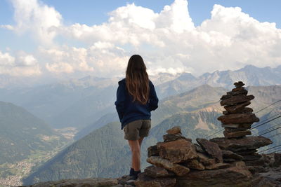 Girl standing on rock against sky
