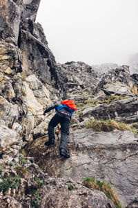 Rear view of hiker with backpack mountain climbing during foggy weather