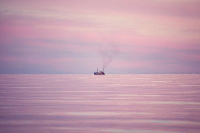 Ship sailing on sea against sky at sunset