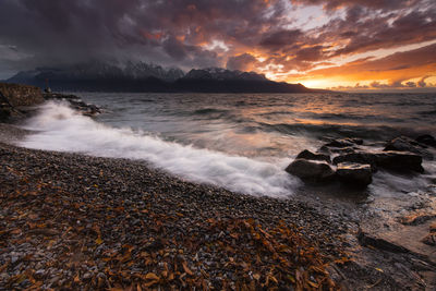 Scenic view of sea against dramatic sky during sunset