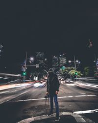 Woman walking on road in city at night