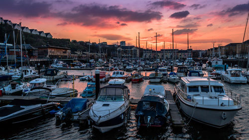 Sailboats moored at harbor during sunset