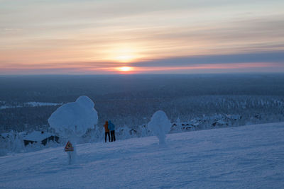 Rear view of people standing against landscape during winter