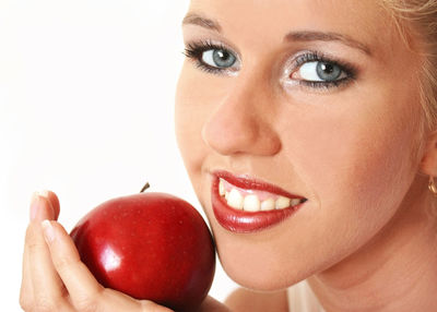 Cropped image of woman holding apple against white background