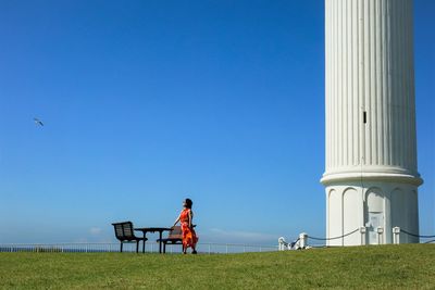 Rear view of man tower against blue sky