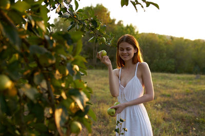 Young woman standing against plants