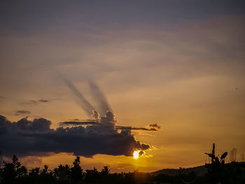 Silhouette of factory against sky during sunset