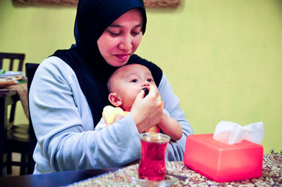 Smiling mother feeding son in restaurant