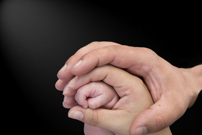 Close-up of hands holding hands against black background