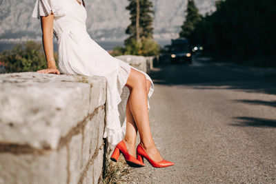 Women leg with red shoes sitting on the road