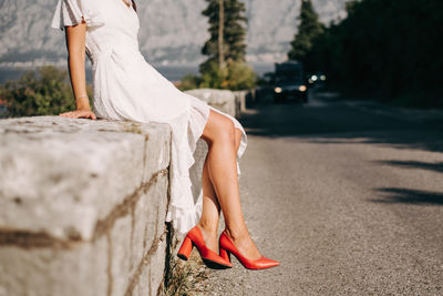 Low section of woman with umbrella on road