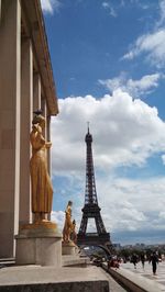 Statue in city against cloudy sky