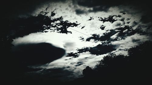 Low angle view of silhouette trees against cloudy sky