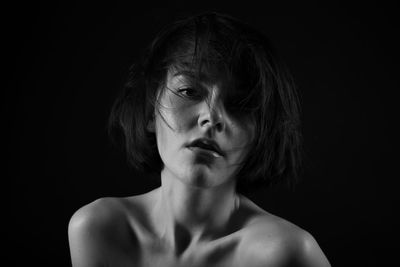 Close-up portrait of young woman against black background