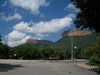 Road by trees in city against sky