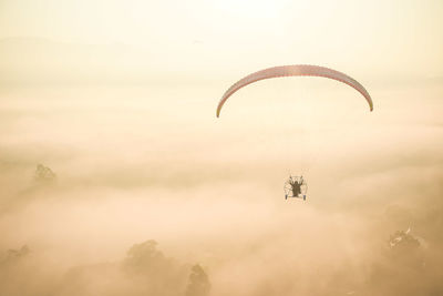 Person paragliding against sky during sunset