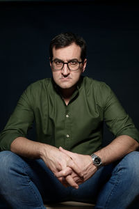 Portrait of mature man sitting against black background