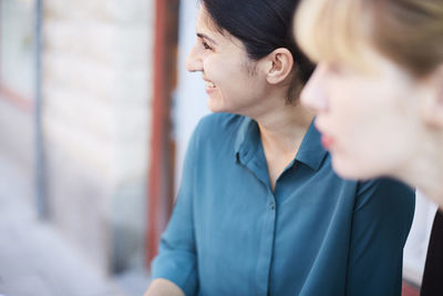 Smiling mid adult businesswoman with female colleague looking away outside office