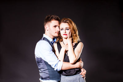 Portrait of young couple kissing against black background