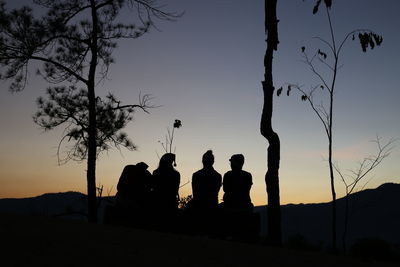 Silhouette people on field against sky during sunset