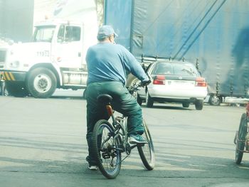 Rear view of man cycling on street