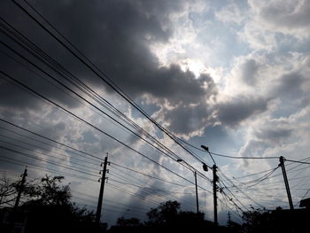 Low angle view of electricity pylon against cloudy sky