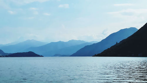 Scenic view of sea by mountains against sky