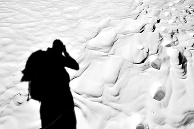 Low section of man walking on snow covered landscape