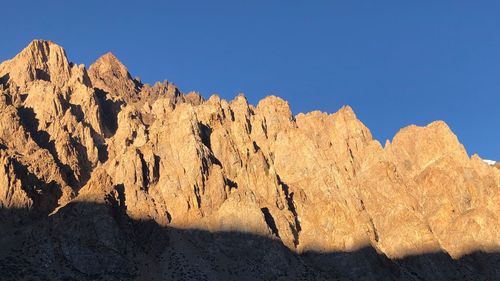 Low angle view of rock formations against clear blue sky