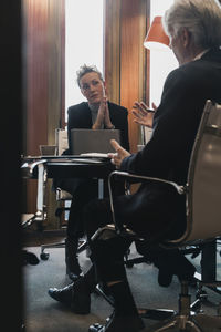 Senior businessman planning strategy with businesswoman at conference table in board room