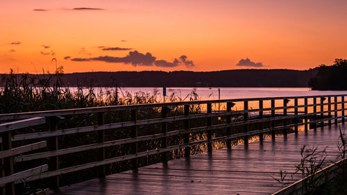 Pier over lake against romantic sky at sunset