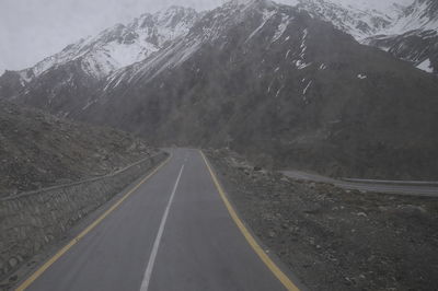 Road amidst mountains against sky during winter