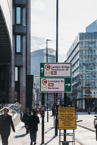 Road sign on street against buildings in city